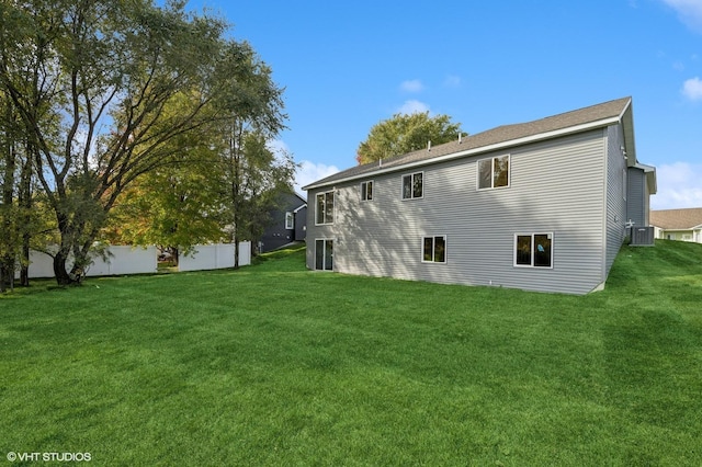 rear view of property featuring central AC and a lawn