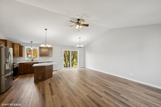 kitchen featuring decorative light fixtures, vaulted ceiling, appliances with stainless steel finishes, dark hardwood / wood-style flooring, and a kitchen island