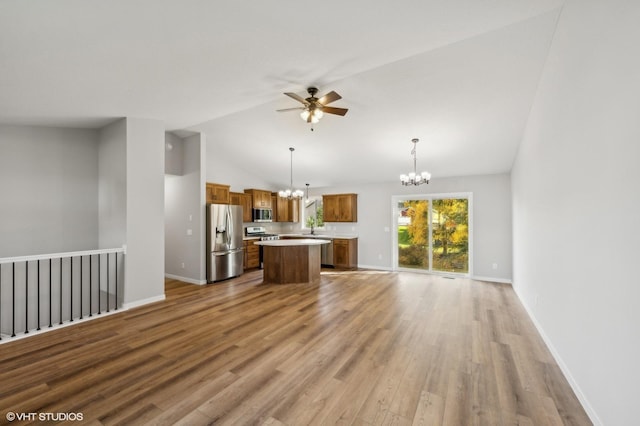 unfurnished living room with vaulted ceiling, sink, ceiling fan with notable chandelier, and light wood-type flooring