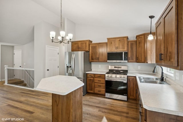 kitchen with stainless steel appliances, decorative light fixtures, sink, and a kitchen island