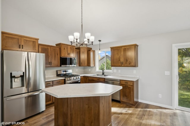 kitchen featuring sink, stainless steel appliances, a center island, light hardwood / wood-style floors, and decorative light fixtures