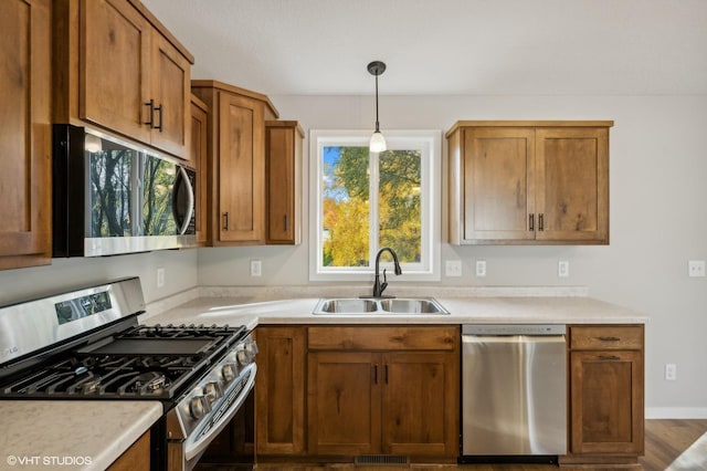 kitchen with appliances with stainless steel finishes, sink, and hanging light fixtures