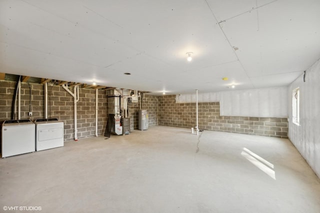 basement featuring heating unit, electric water heater, and independent washer and dryer