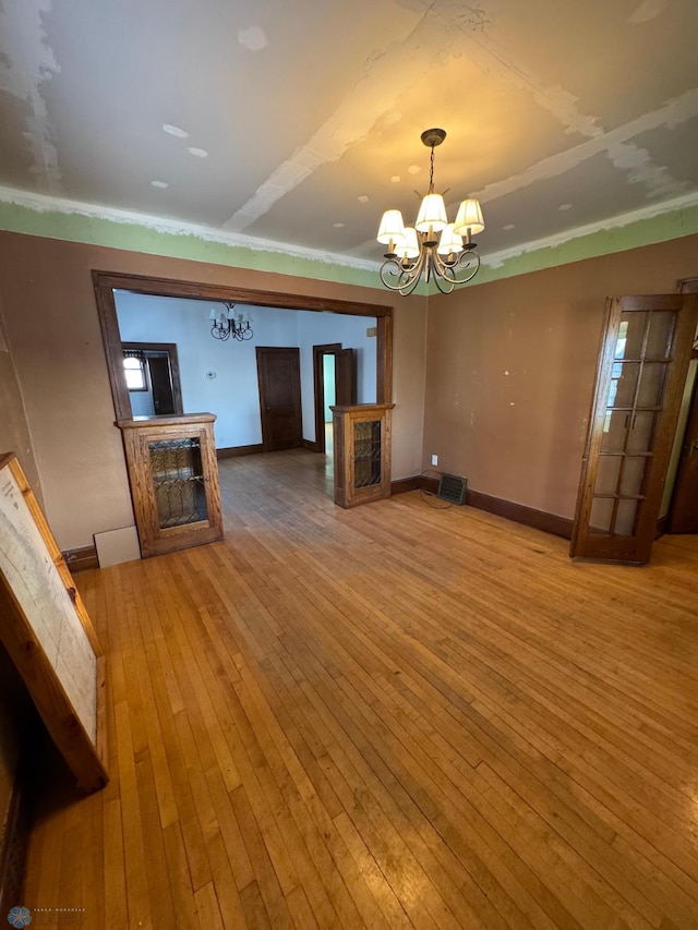 unfurnished living room featuring hardwood / wood-style floors, a notable chandelier, a fireplace, and ornamental molding