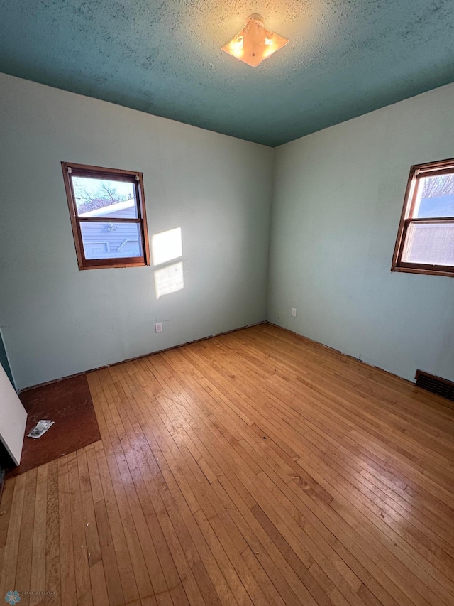 spare room with light hardwood / wood-style flooring and a textured ceiling