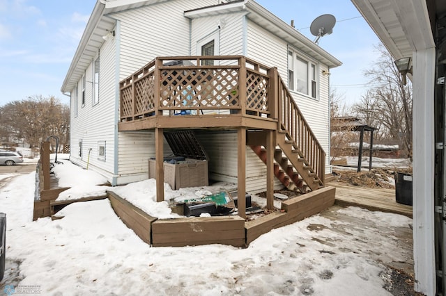 snow covered rear of property featuring stairs and a wooden deck