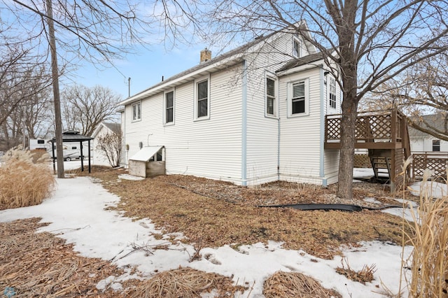 view of snow covered exterior with a deck and a chimney