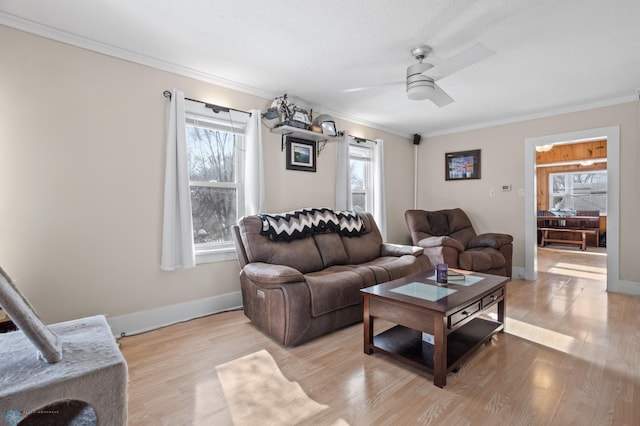 living room featuring ornamental molding, light wood-style floors, baseboards, and a ceiling fan