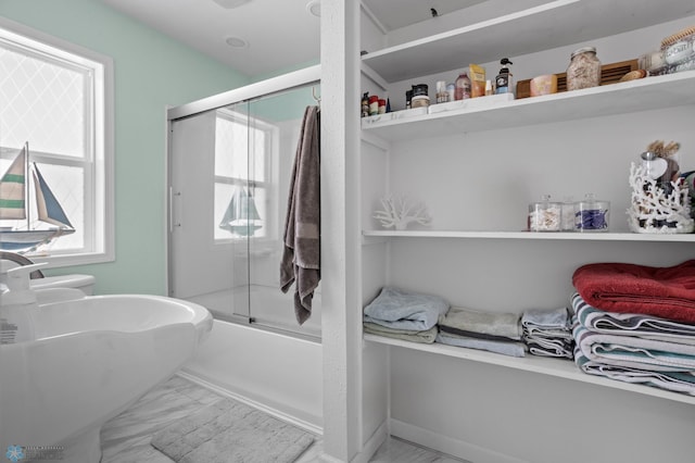 bathroom featuring marble finish floor, combined bath / shower with glass door, and toilet