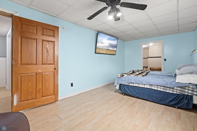 bedroom featuring a ceiling fan, a paneled ceiling, baseboards, and light wood finished floors