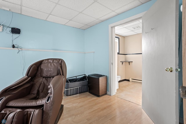 office space featuring light wood-type flooring, a baseboard radiator, and a drop ceiling