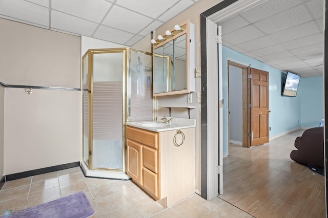 full bathroom with a shower stall, baseboards, a drop ceiling, and vanity