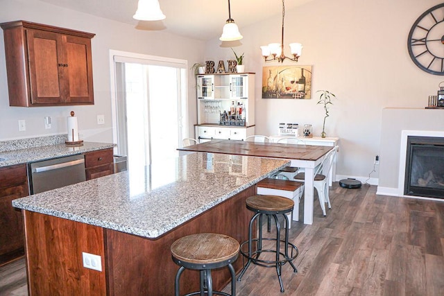 kitchen featuring dishwasher, light stone countertops, dark hardwood / wood-style flooring, and decorative light fixtures