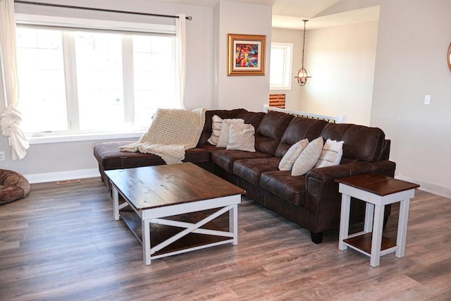 living room featuring dark wood-type flooring, plenty of natural light, and a notable chandelier