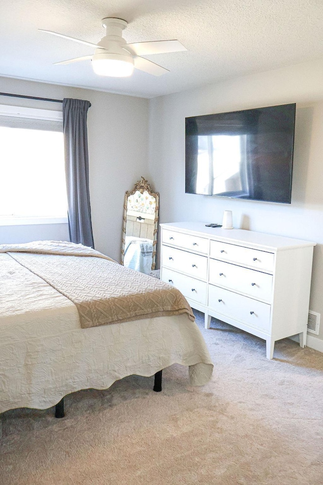 carpeted bedroom with ceiling fan and a textured ceiling