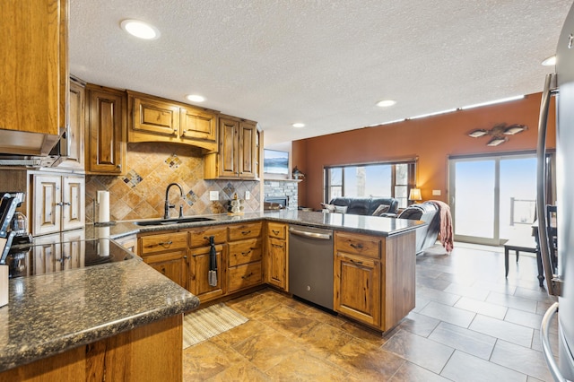 kitchen featuring brown cabinetry, a peninsula, stainless steel dishwasher, and a sink