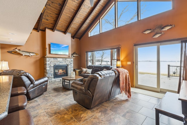 living area with a stone fireplace, wooden ceiling, high vaulted ceiling, and beam ceiling