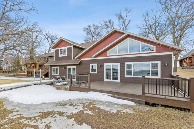 snow covered back of property with a deck