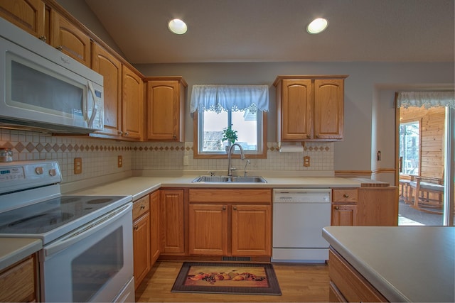 kitchen featuring sink, white appliances, light hardwood / wood-style flooring, backsplash, and vaulted ceiling