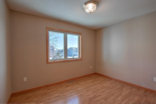 spare room with a textured ceiling and light wood-type flooring