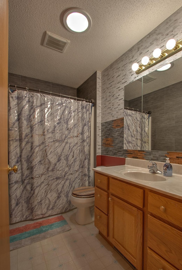 bathroom featuring vanity, toilet, a textured ceiling, and tile walls