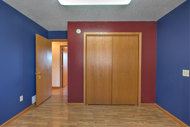 unfurnished bedroom with light hardwood / wood-style flooring, a closet, and a textured ceiling