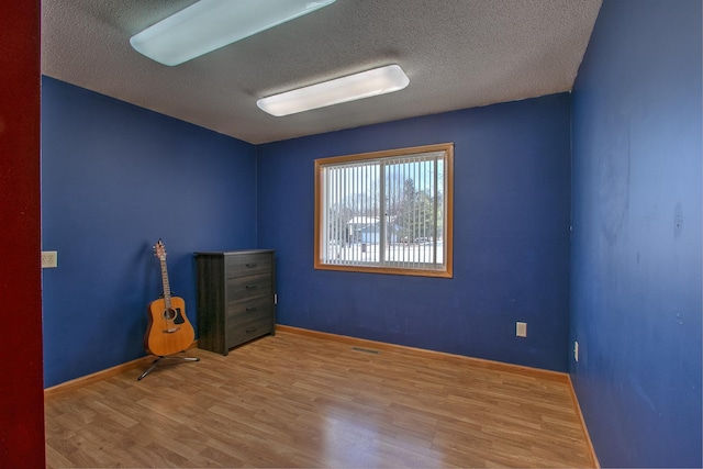 unfurnished room with light hardwood / wood-style floors and a textured ceiling