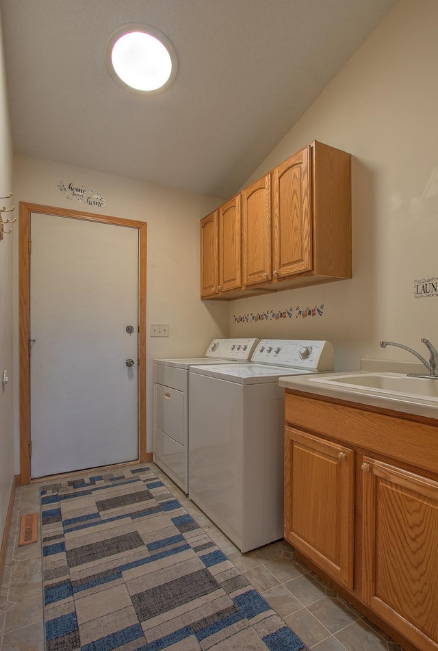 laundry area with cabinets, separate washer and dryer, sink, and dark tile patterned floors