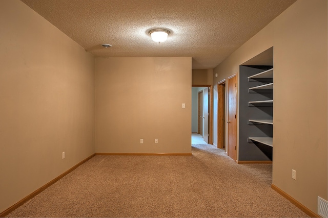 carpeted empty room with a textured ceiling