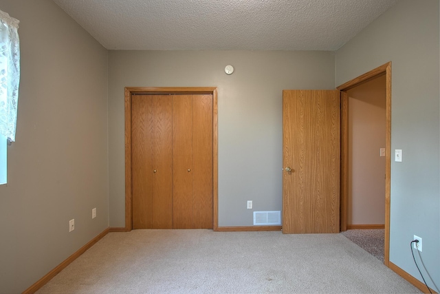 unfurnished bedroom with light colored carpet, a textured ceiling, and a closet