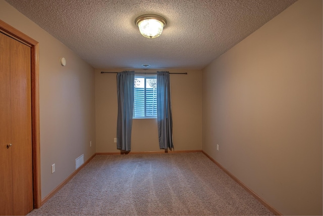 spare room featuring carpet floors and a textured ceiling