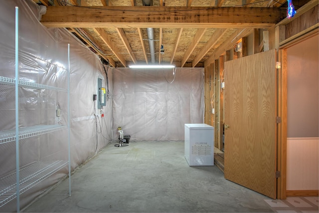 basement featuring electric panel and refrigerator