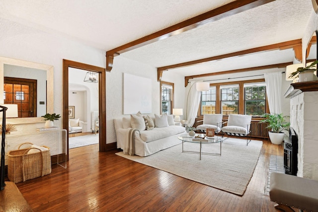 living room featuring beam ceiling, dark wood-type flooring, and a textured ceiling