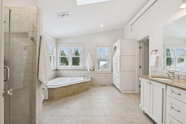 bathroom with tile patterned floors, plenty of natural light, vaulted ceiling with skylight, and shower with separate bathtub