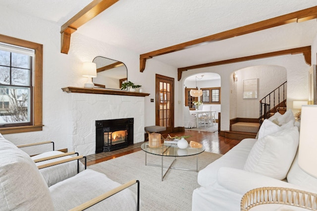 living room with beamed ceiling, wood-type flooring, plenty of natural light, and a textured ceiling