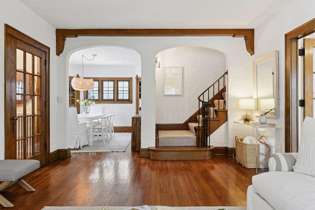 interior space with a textured ceiling, dark hardwood / wood-style floors, and beamed ceiling