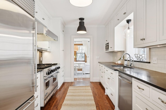 kitchen with built in appliances, pendant lighting, and white cabinets