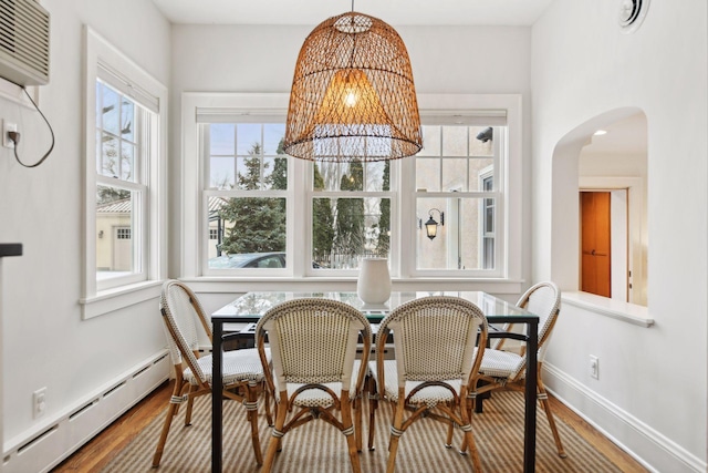 dining space featuring an inviting chandelier, hardwood / wood-style flooring, a wall unit AC, and a baseboard heating unit