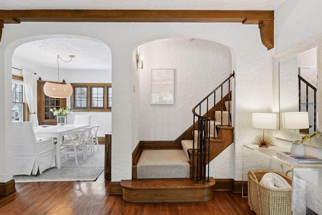 staircase with hardwood / wood-style flooring, a textured ceiling, and beamed ceiling