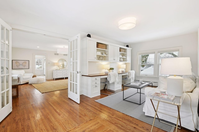 interior space featuring french doors, built in desk, and light wood-type flooring