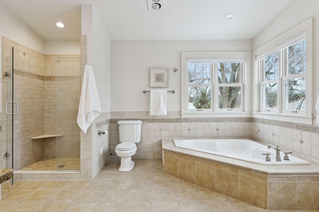 bathroom with tile patterned floors, toilet, separate shower and tub, and tile walls