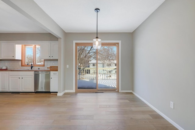 kitchen with dishwasher, white cabinetry, hanging light fixtures, plenty of natural light, and decorative backsplash