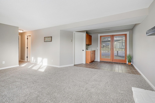 unfurnished living room featuring french doors, light carpet, and a textured ceiling