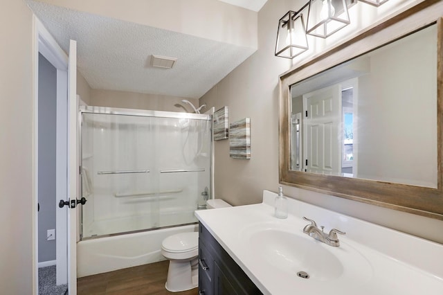 full bathroom with toilet, shower / bath combination with glass door, a textured ceiling, vanity, and hardwood / wood-style flooring