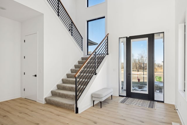 foyer featuring a towering ceiling, plenty of natural light, and light wood-type flooring