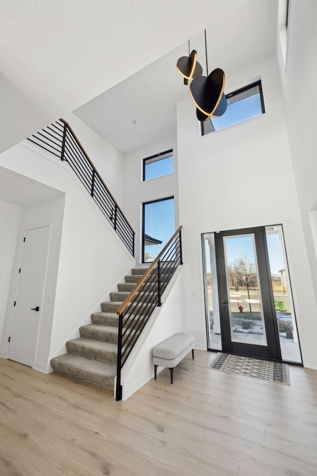 foyer with stairs, wood finished floors, and a wealth of natural light