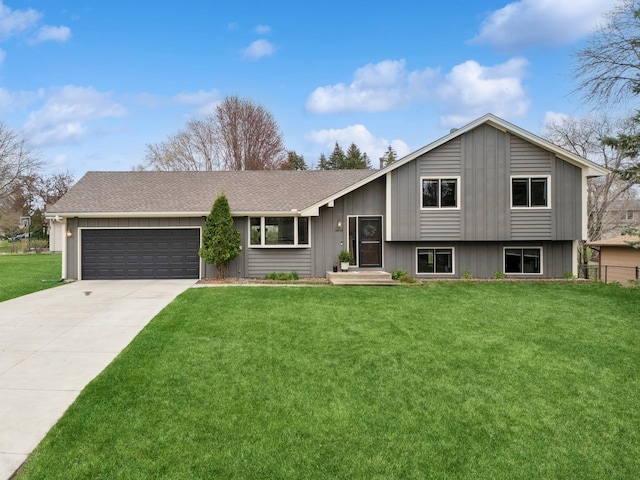 tri-level home with roof with shingles, an attached garage, driveway, and a front lawn