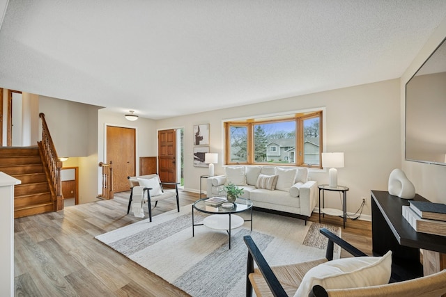 living room with light wood-type flooring, baseboards, and stairway