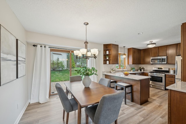 dining space featuring a textured ceiling, light wood-style flooring, and a chandelier