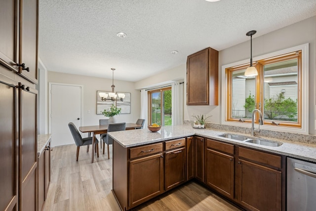kitchen with stainless steel dishwasher, a peninsula, a textured ceiling, and a sink